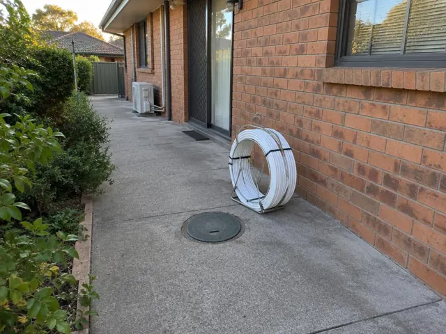 Concrete side path beside a brick house with a capped access opening and tidy reinstated surface in Baulkham Hills